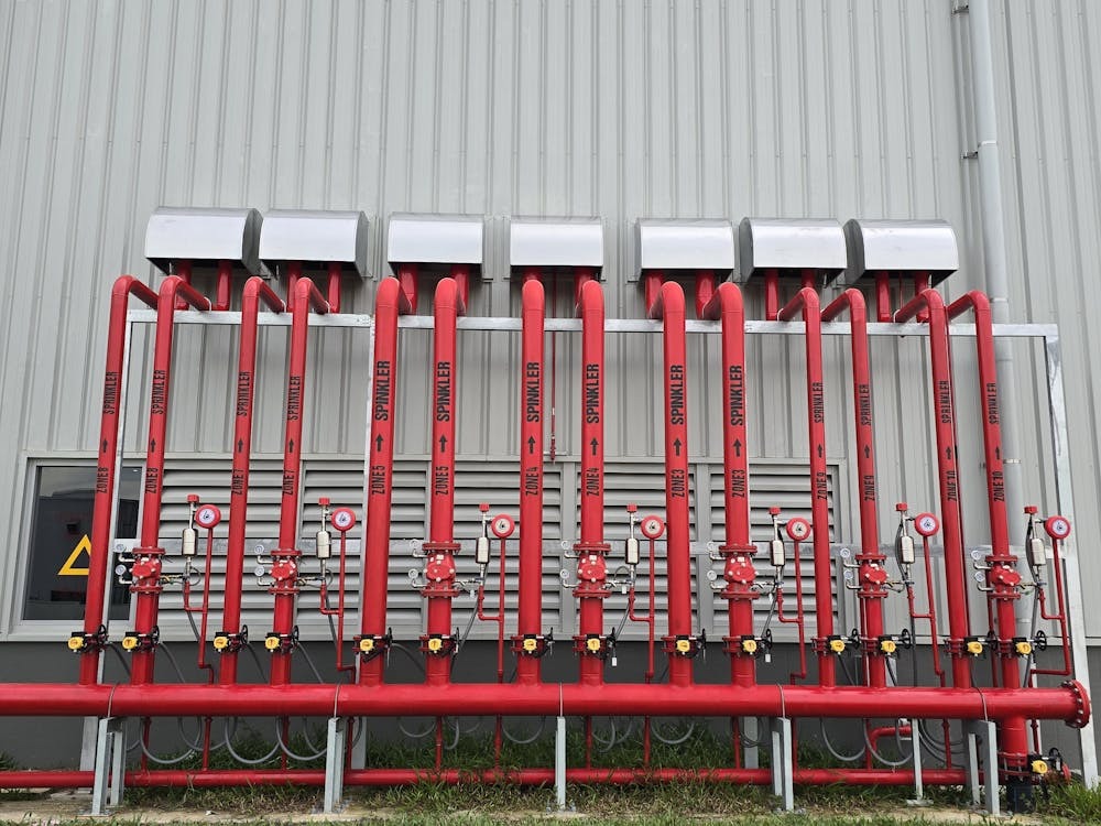 Overhead view of industrial fire sprinkler system pipes installed in a commercial facility, representing the approved automatic fire suppression requirements mandated under 2024 IFC fire code lithium battery storage regulations.