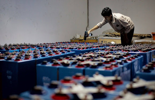 An industrial worker in a warehouse conducting an inspection of battery storage units, representing the enforcement of fire code lithium battery storage regulations and the role of on-site safety assessments in IFC 2024 compliance.