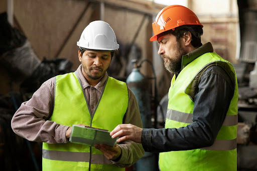 Two safety personnel in hard hats and safety vests conducting a facility review, representing the DOT hazmat inspection stage that opens the hazmat enforcement process.