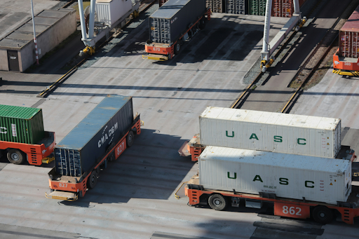 Shipping containers being transported through an intermodal freight terminal, illustrating the movement of hazardous materials that may require a DOT special permit.
